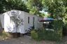 Camping Hérault : Mobil home et sa terrasse conviviale ombragée par de grands arbres et délimitée par des haies